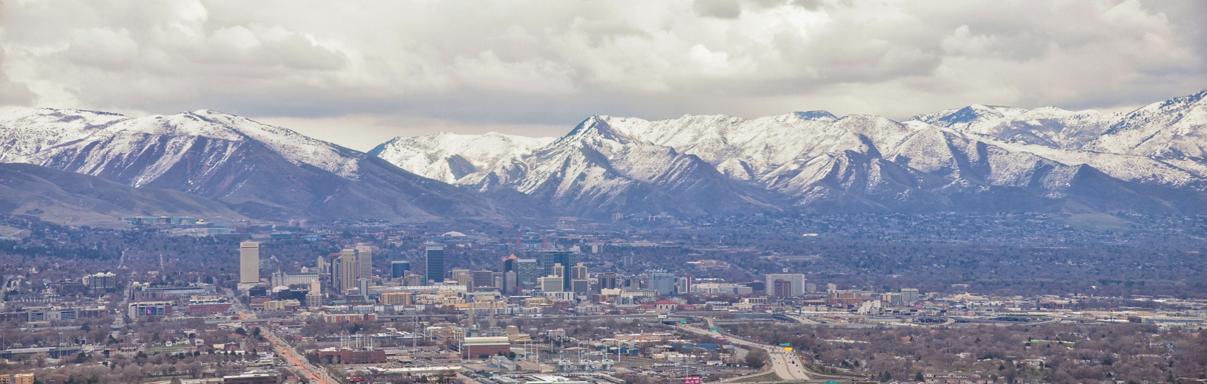 Downtown Salt Lake City Panoramic view of Wasatch Front Rocky Mountains from airplane in early spring winter with melting snow and cloudscape. Utah, USA.