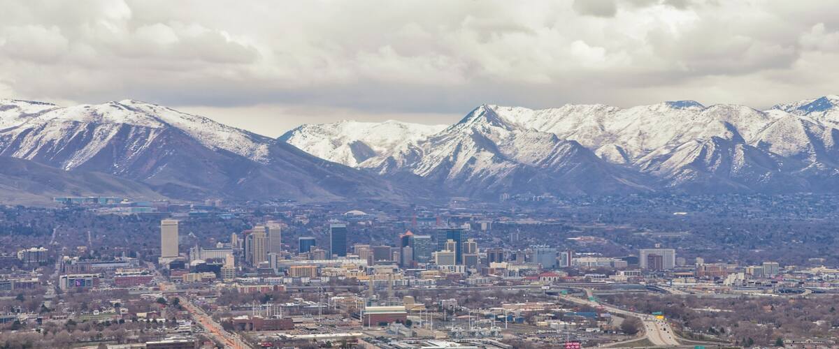 Downtown Salt Lake City Panoramic view of Wasatch Front Rocky Mountains from airplane in early spring winter with melting snow and cloudscape. Utah, USA.