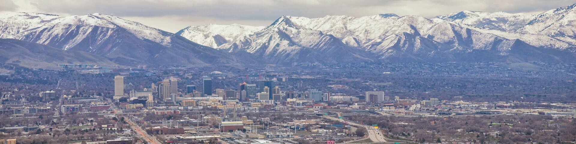 Downtown Salt Lake City Panoramic view of Wasatch Front Rocky Mountains from airplane in early spring winter with melting snow and cloudscape. Utah, USA.