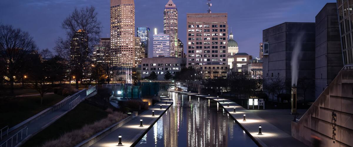Indianapolis city lights with reflections in the Central Canal at dusk.