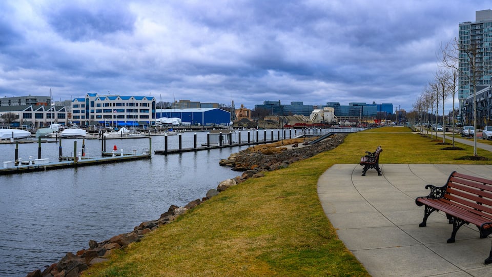 Stamford City Harbor Point Landscape with tall office buildings, park benches, boardwalk footpaths, and moored boats at the dock on a dramatic stormy winter in Connecticut
