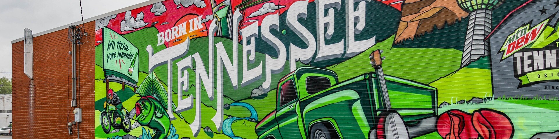 Um mural em uma parede de tijolos com o texto 'BORN IN TENNESSEE' e 'TENNIS'.
