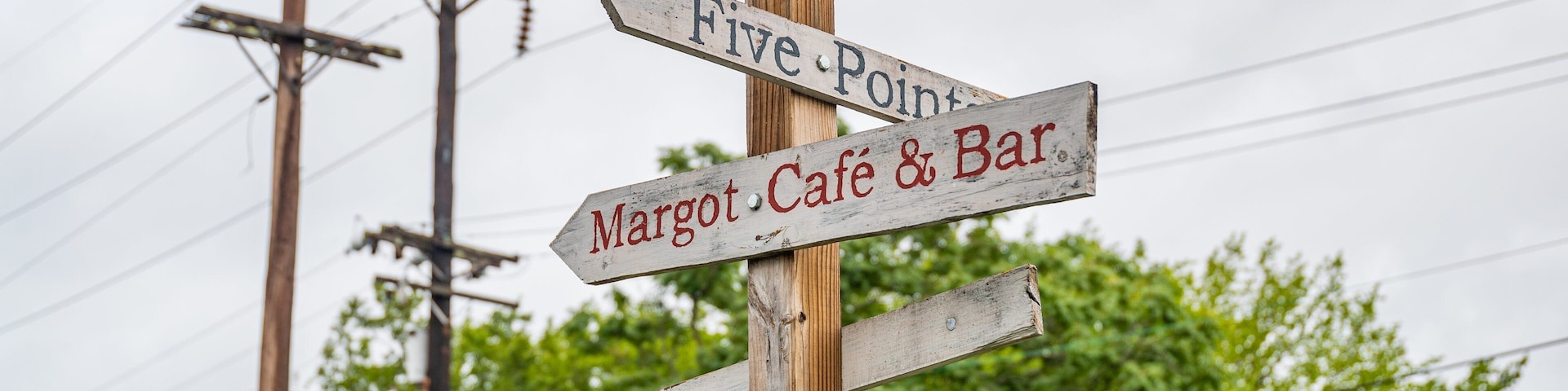 Ein hölzernes Wegweiser mit Hinweisen zu 'Five Point' und 'Margot Café & Bar'.