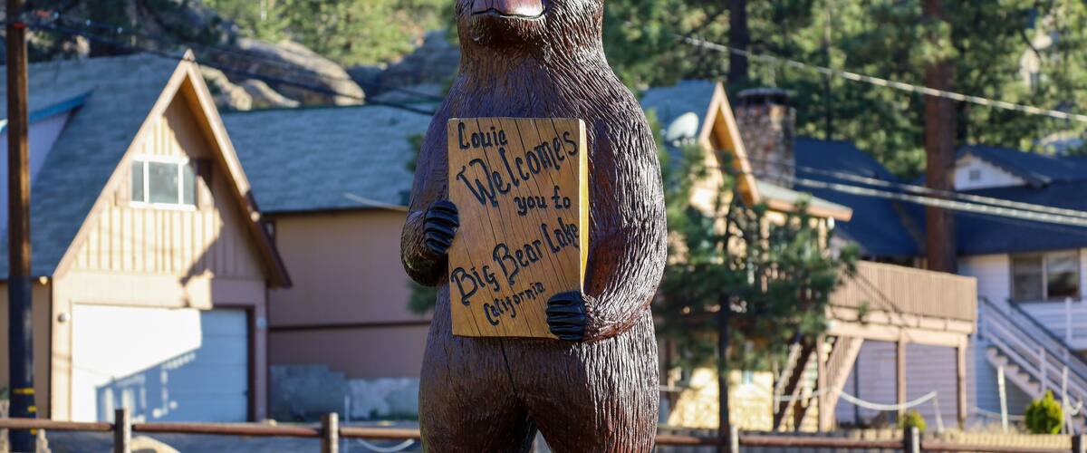 Louie the wooden bear statue holding a welcome to Big Bear Lake sign at Boulder Bay Park in Big Bear, California.
