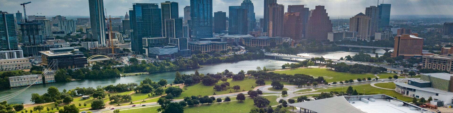 A city skyline with modern skyscrapers, a river, and a park with winding paths.