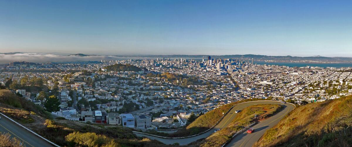A panoramic view of a city with a dense urban center, a prominent skyline, and a coastal backdrop.