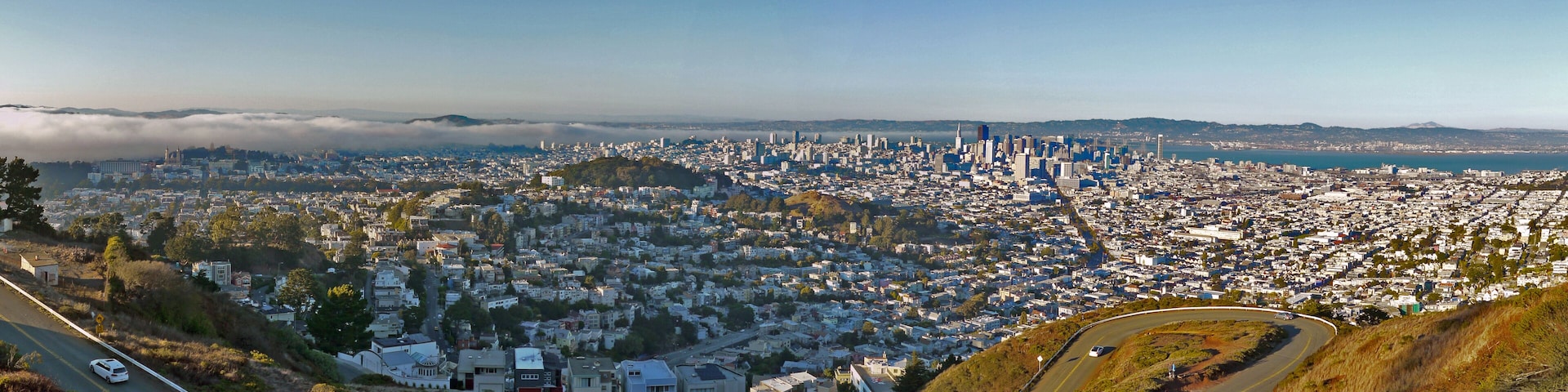A panoramic view of a city with a dense urban center, a prominent skyline, and a coastal backdrop.