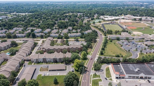 Vista aérea de una zona residencial con edificios, un campo deportivo y un estacionamiento.