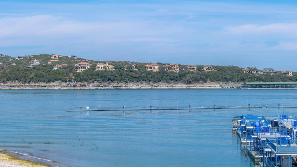 Panoramic view of Lake Austin with docked party boats near residences at Austin, Texas. There are flat boats on the right below near the shore across the sloped residential area across.
