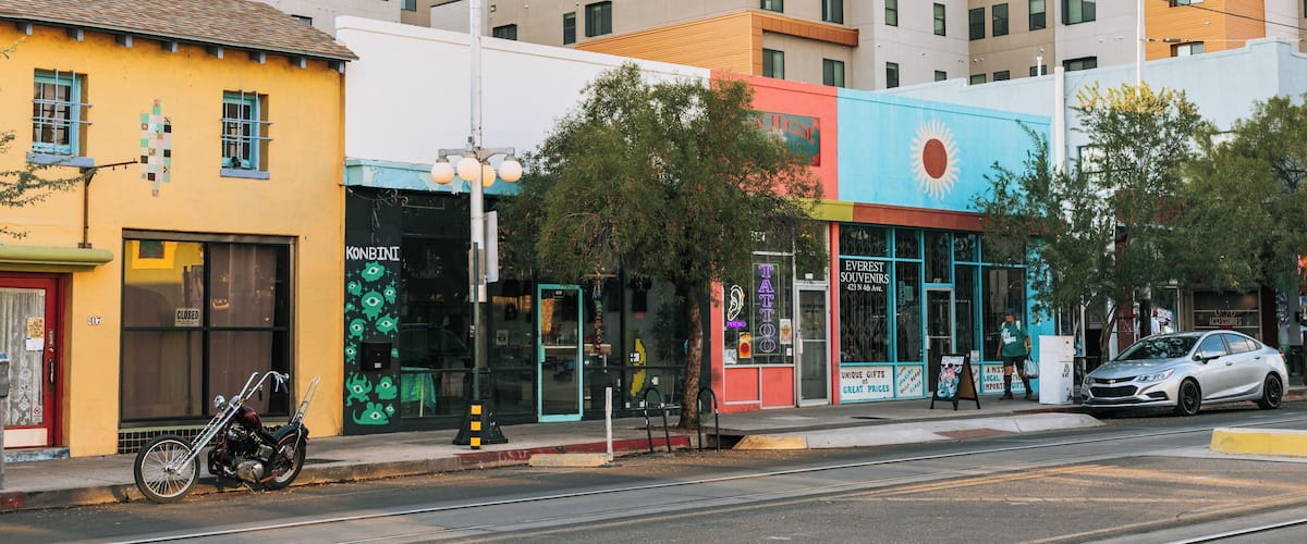 A street with colorful buildings, a motorcycle, and a car.