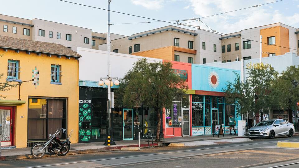 A street with colorful buildings, a motorcycle, and a car.