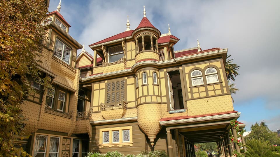 A large, ornate Victorian-style house with a red roof and multiple windows.