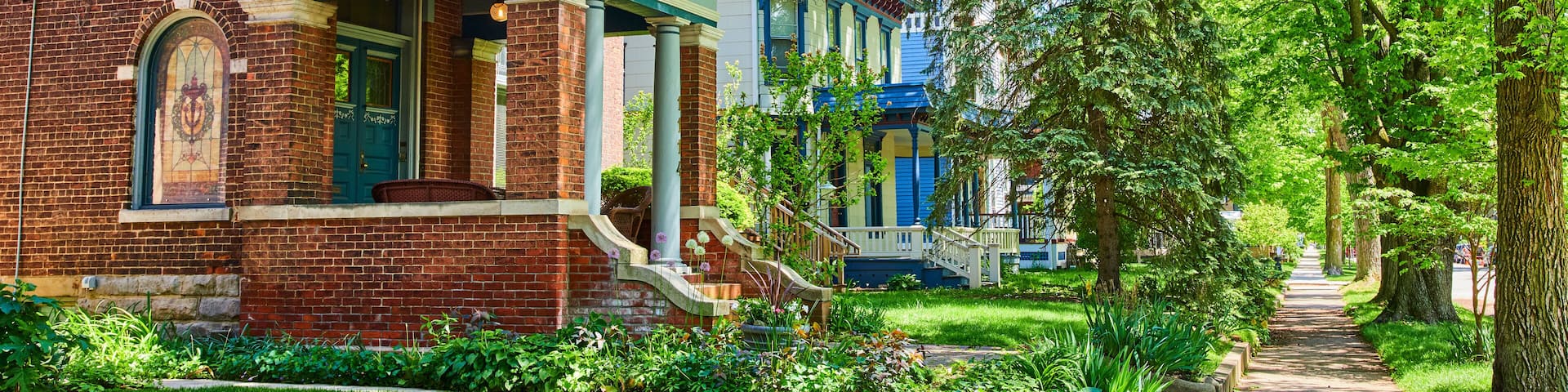 Charming Suburban Street with Victorian and Colonial Houses, Lush Greenery