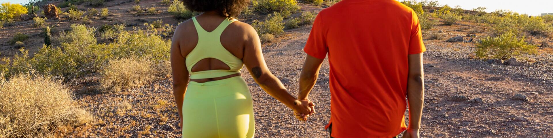 Happy black couple together hiking view from behind and hands held