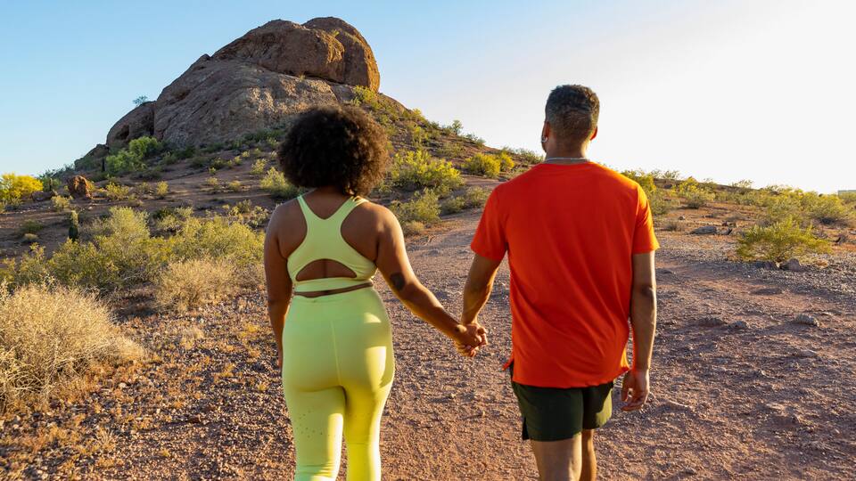 Happy black couple together hiking view from behind and hands held