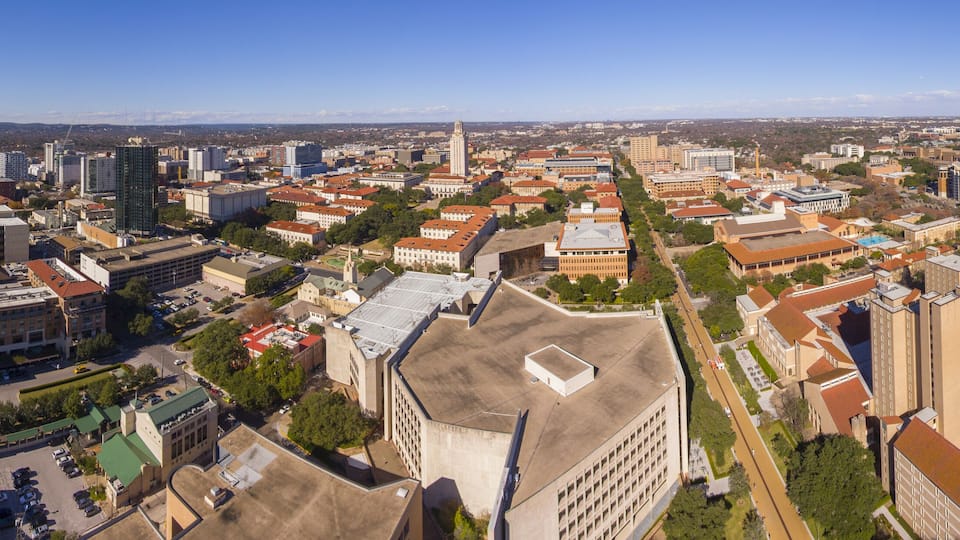 A cityscape with a mix of modern and historic buildings, a prominent church, and a clear blue sky.