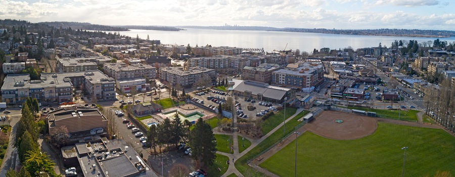 Une vue aérienne d’une ville, avec une vaste étendue d’eau en arrière-plan, un terrain de baseball et divers bâtiments.