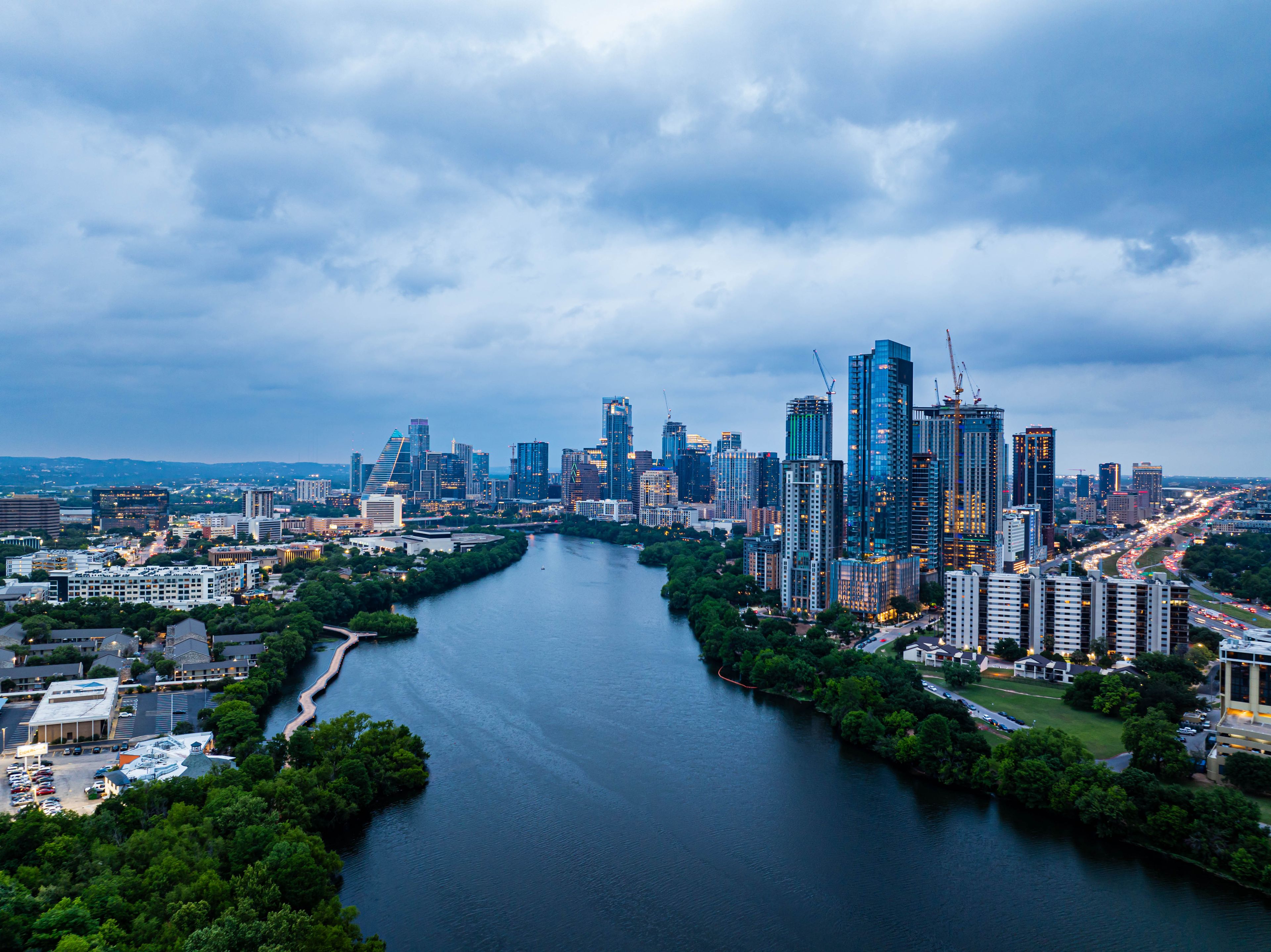 A river flowing through a city with modern skyscrapers and a mix of greenery.
