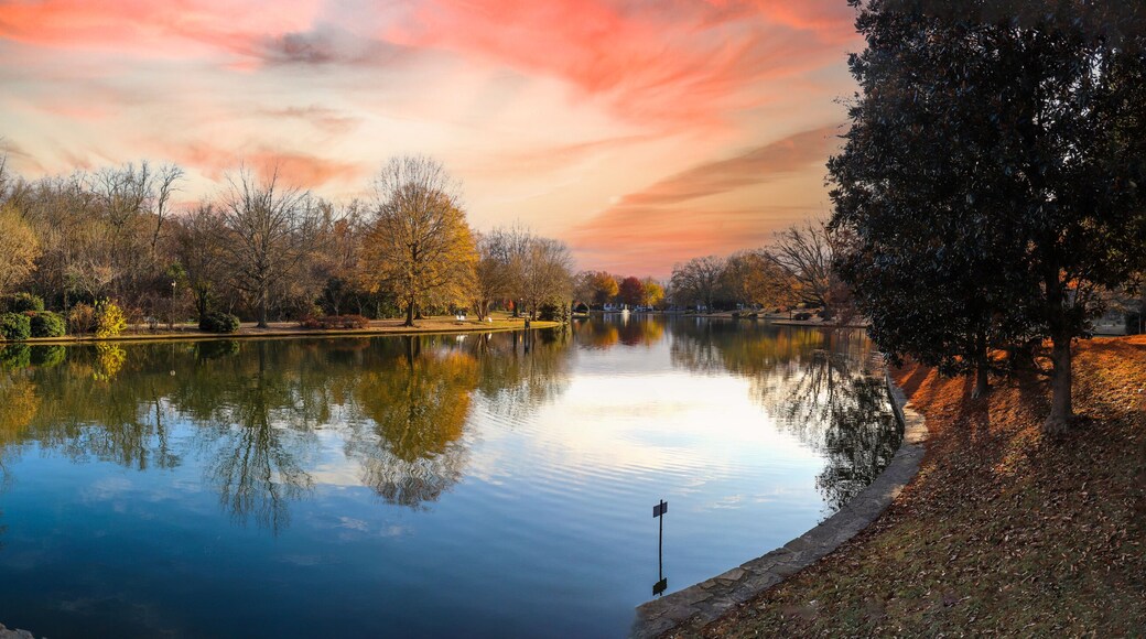 a panoramic shot of a gorgeous autumn landscape with lake and autumn colored trees reflecting off the water with red sky and clouds at sunset at Freedom Park in Charlotte North Carolina USA