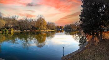 a panoramic shot of a gorgeous autumn landscape with lake and autumn colored trees reflecting off the water with red sky and clouds at sunset at Freedom Park in Charlotte North Carolina USA