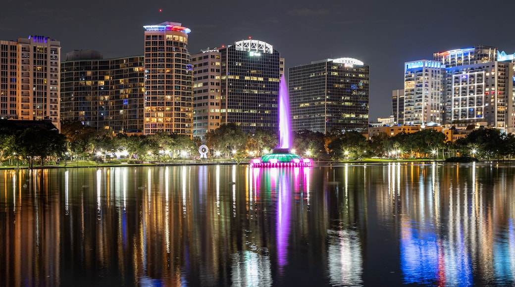 Night time panoramic photo in downtown Orlando of Lake Eola with the fountain lit up and colorful reflections in the water