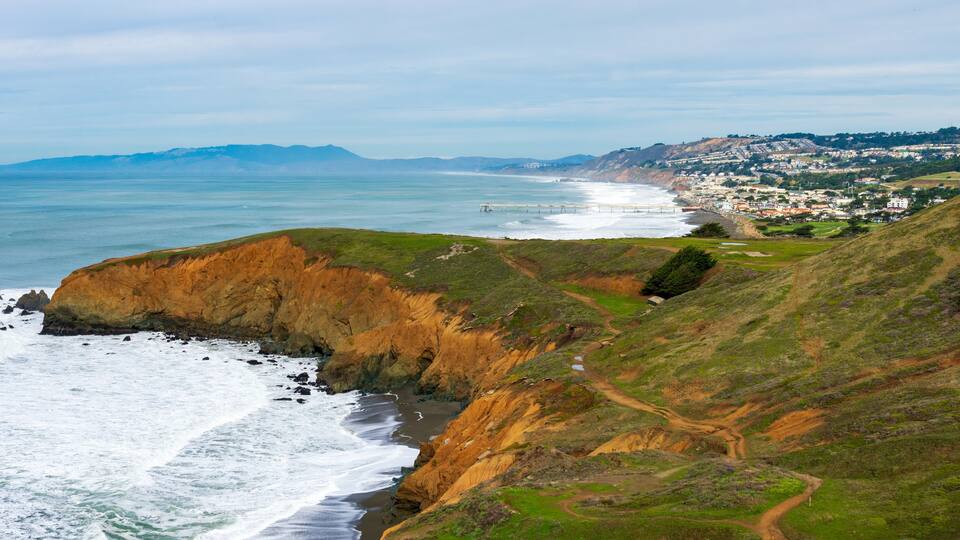 Panoramic scenic view of California rugged Pacific ocean coastline with green hills near Pacifica during overcast winter day