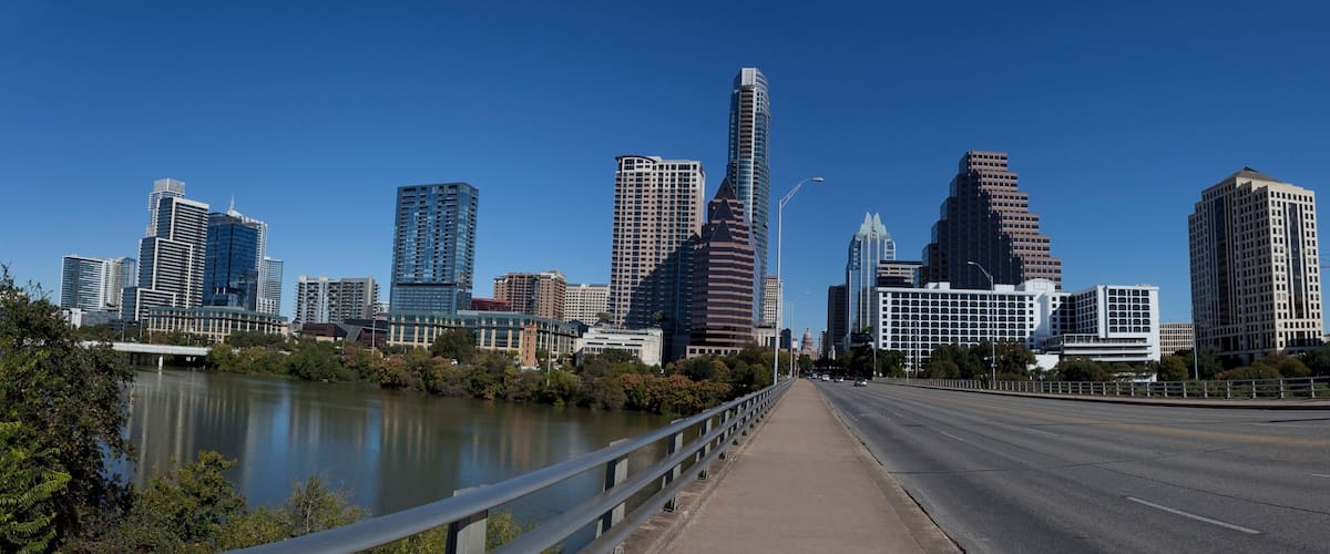 A city skyline with modern high-rise buildings, a river, and a bridge.