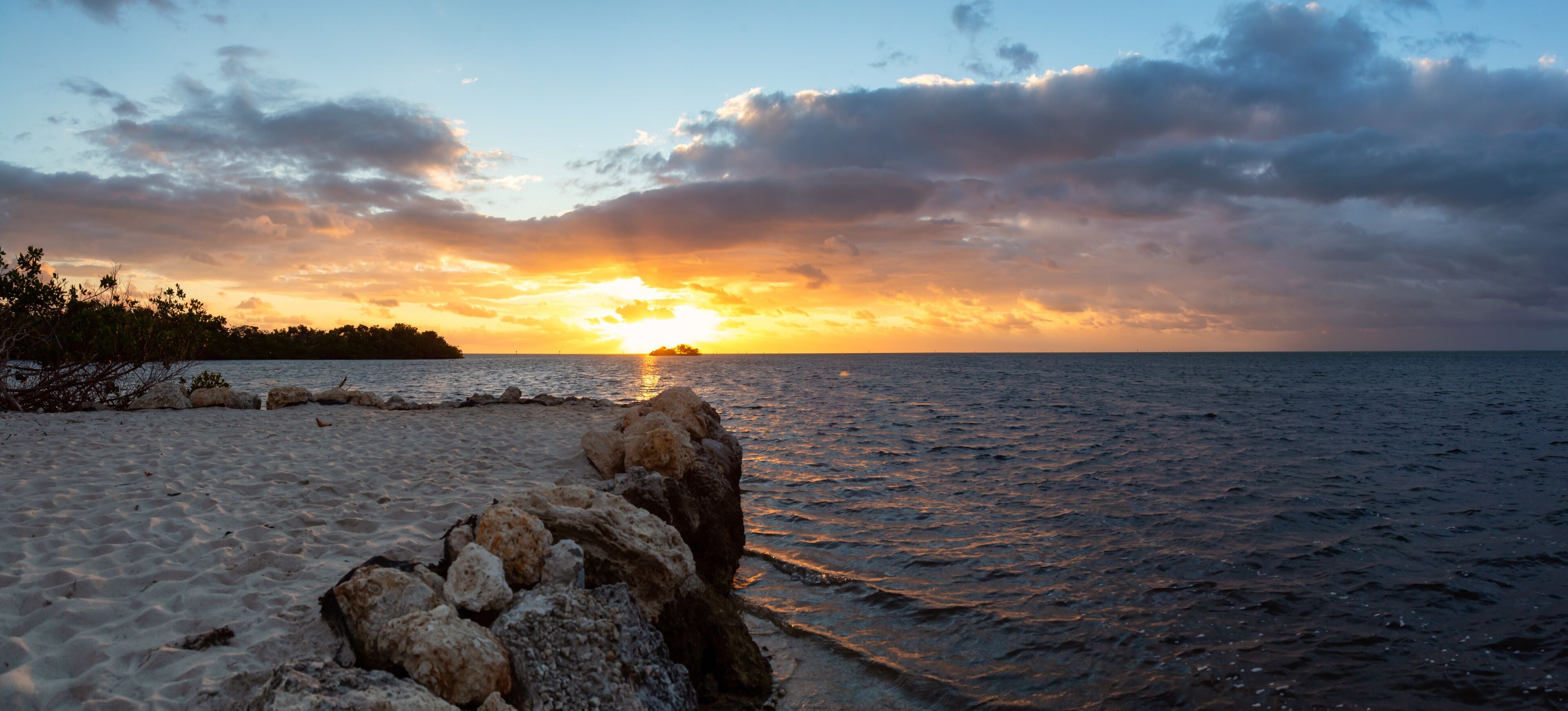 Dramatic cloudy sunrise viewed on a tropical sandy beach at the Atlantic Ocean Shore. Plantation Key, Florida Keys, Florida, United States.