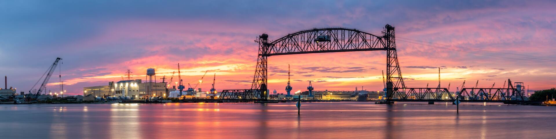 Vertical lift bridge for railroad over the Elizabeth River on the border of Norfolk and Chesapeake Virginia against a beautiful red, purple, pink, and blue sunset