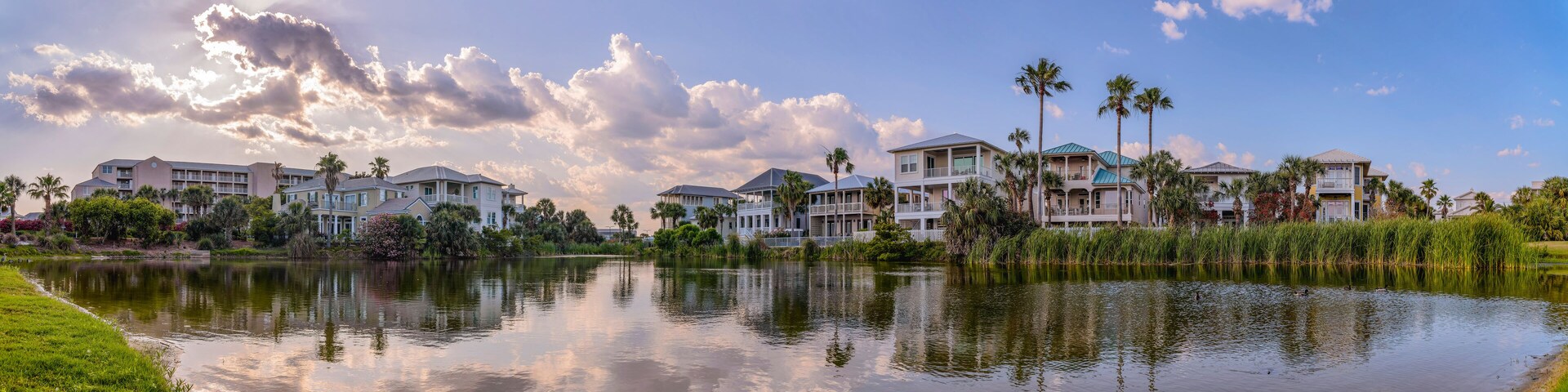 Panorama of houses and buildings around a freshwater lake in Destin Florida. Scenic nature landscape with water reflecting trees and blue sky on a sunny day.