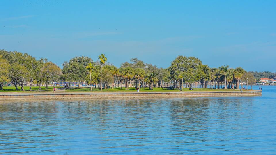 A calm lake with a park and trees along the shore.