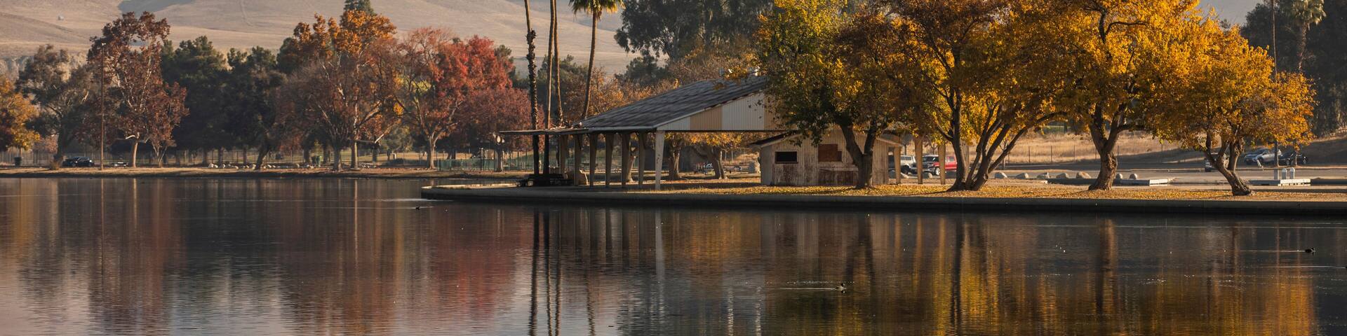 A calm lake with reflections of trees and a small building.