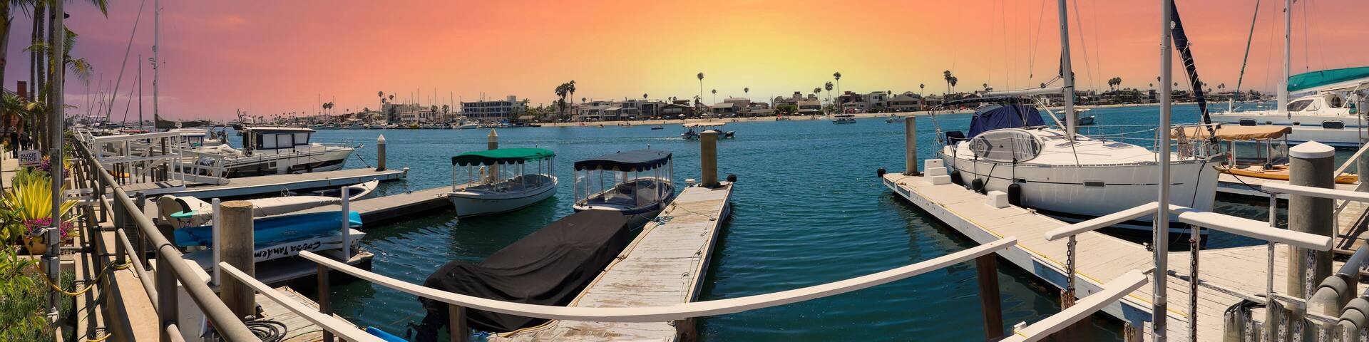 a gorgeous summer landscape at Naples Canals with people on paddle boards on blue ocean water with boats docked along the banks and homes with lush green palm trees and powerful clouds at sunset