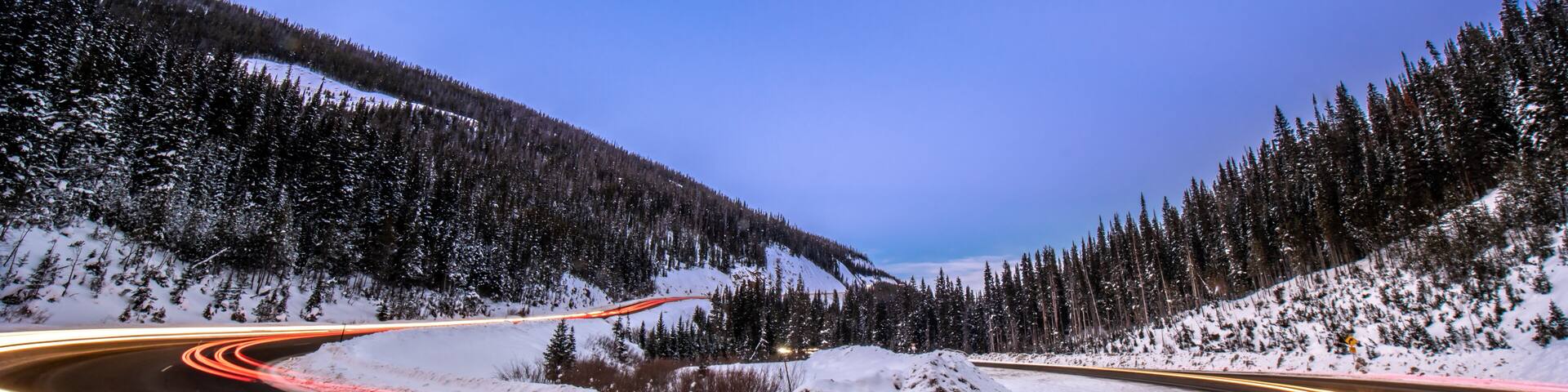 A winding road through a snowy mountainous landscape at dusk.
