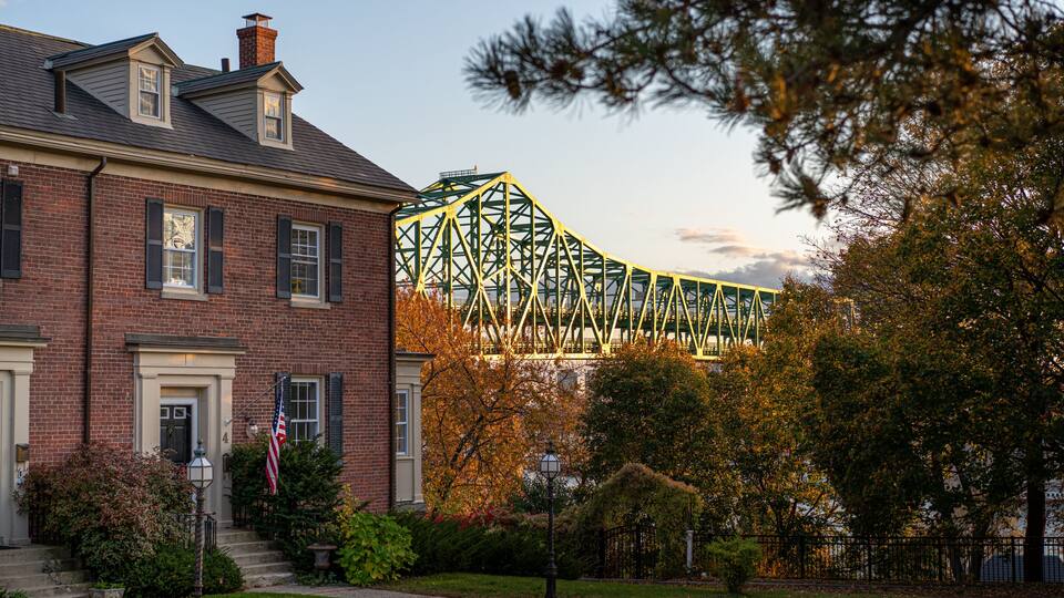 Brick house and american flag, background Maurice J. Tobin Memorial Bridge over the Mystic River, Boston Massachusetts