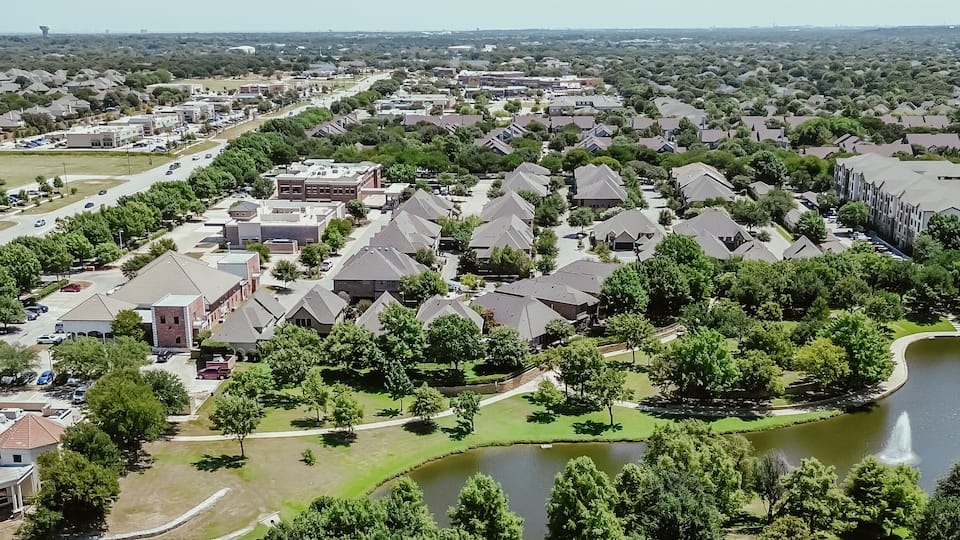 A residential area with houses, a road, and a lake.