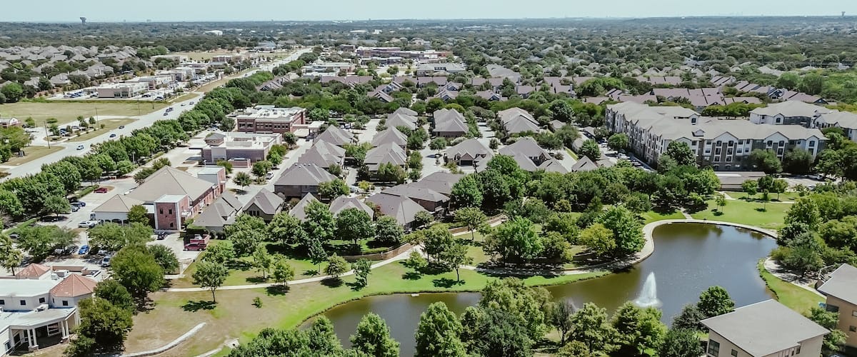 A residential area with houses, a road, and a lake.