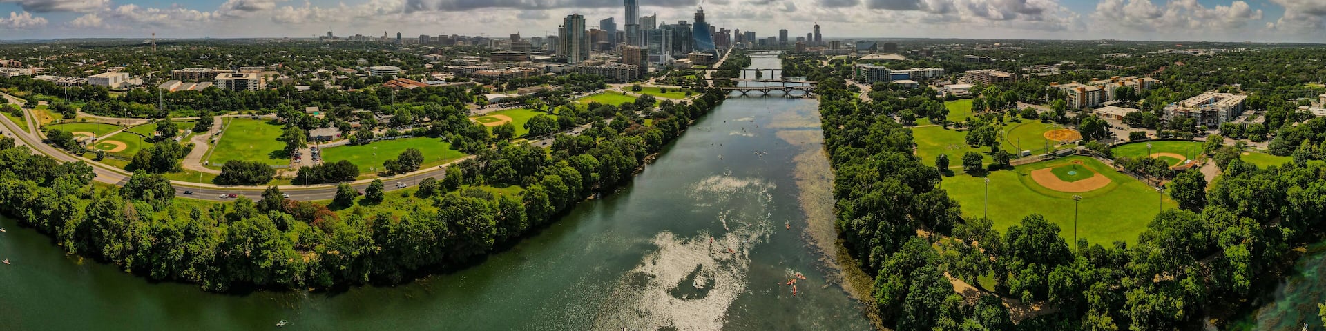 A river with a bridge, surrounded by parks and a city skyline.