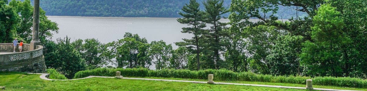A park with a lake, a stone monument, and a path.
