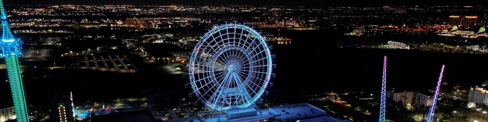 Illuminated Ferris Wheel At Orlando In Florida United States. Colorful Ferris Wheel. Illuminated City. Night Life Landscape. Illuminated Ferris Wheel At Orlando In Florida United States.
