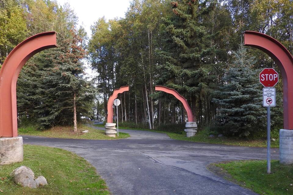 Ein Stoppschild am Eingang eines bewaldeten Bereichs mit einem Fußweg.