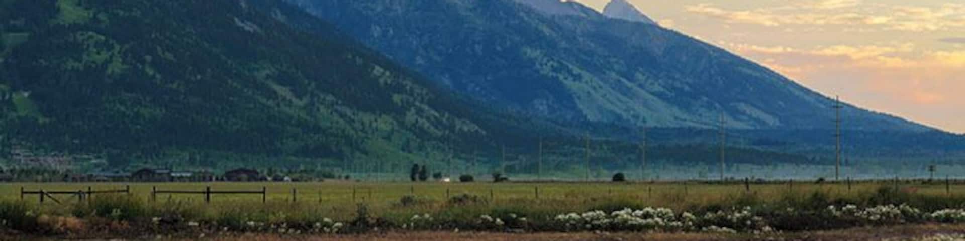 Just before dawn and the early sunlight is illuminating the skies and the Grand Tetons.
It was mid-July when this photo yet the mountains have snow on them still.
