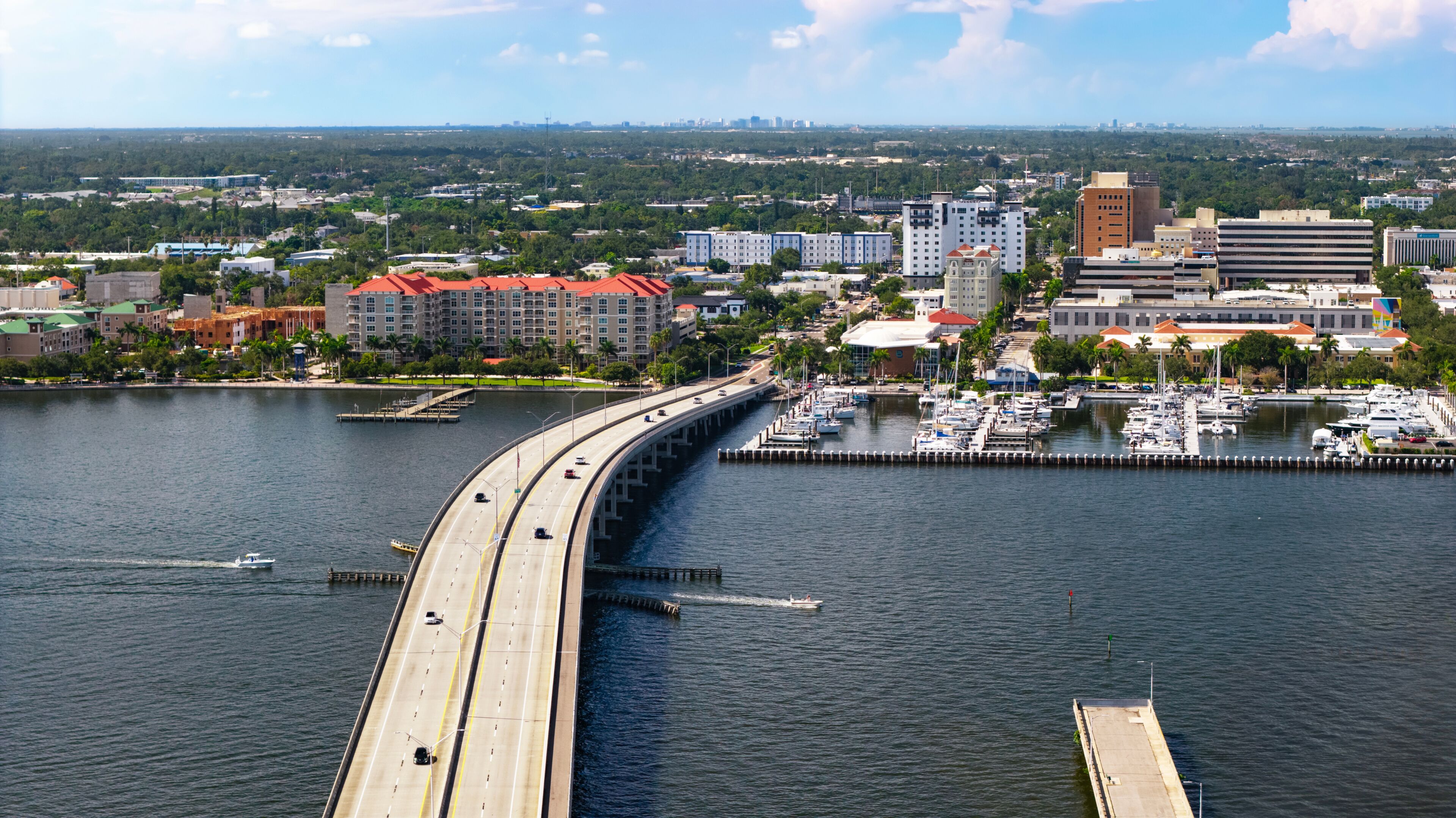 Aerial view of the Green Bridge connecting Palmetto to downtown Bradenton, FL. Vehicles traverse the bridge as recreational boats on the Manatee River head towards Tampa Bay and the Gulf of America.