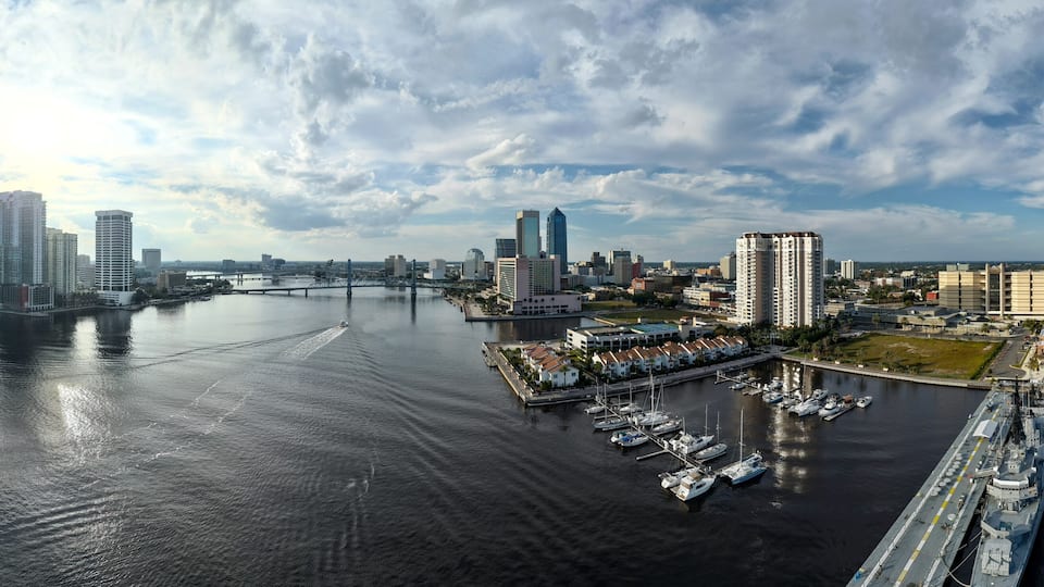 Aerial view of the St. Johns River reflecting the sunlight, cutting through the modern skyline and marina, Jacksonville, Florida, United States.