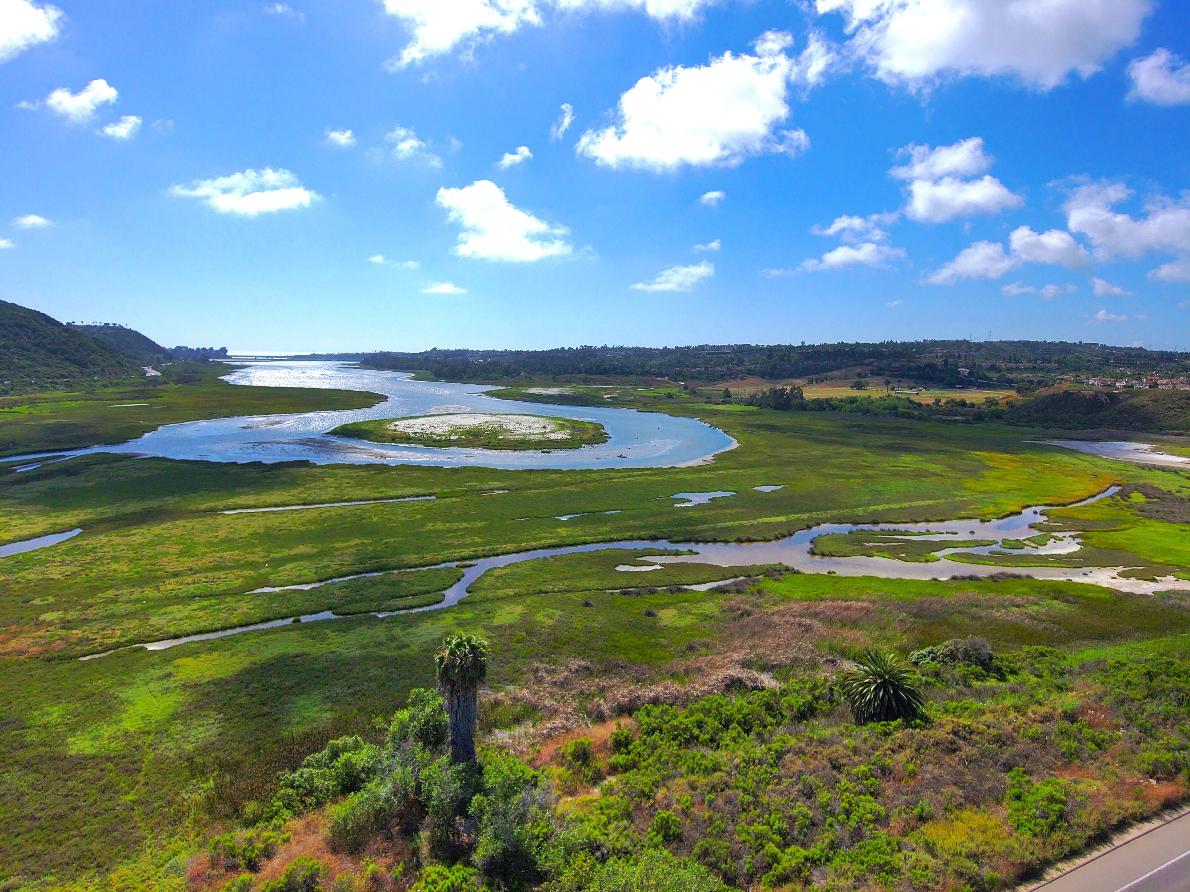 aerial shot of a gorgeous summer landscape at Batiquitos Lagoon with blue waters, lush green trees and blue sky background with clouds in Carlsbad California USA