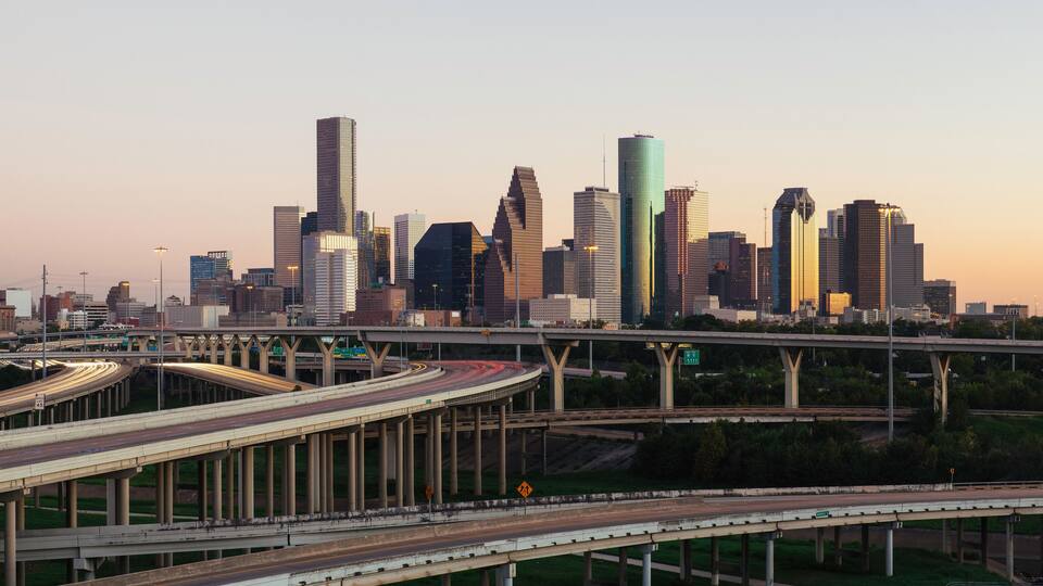 A city skyline with modern skyscrapers and a complex network of highways.