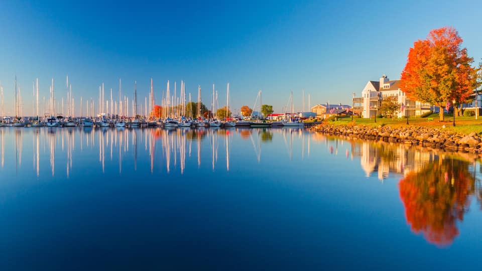 USA, Wisconsin. Panoramic view of Fall colors reflected on the still waters of the harbor in Bayfield on Lake Superior.