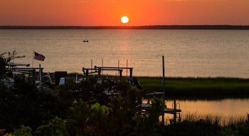 Sunset on Bogue Sound with brilliant orange purple red American flag and men in boat