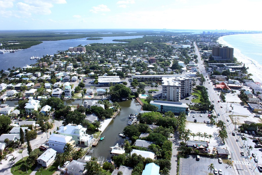 A coastal cityscape with a marina, dense housing, and a beach.