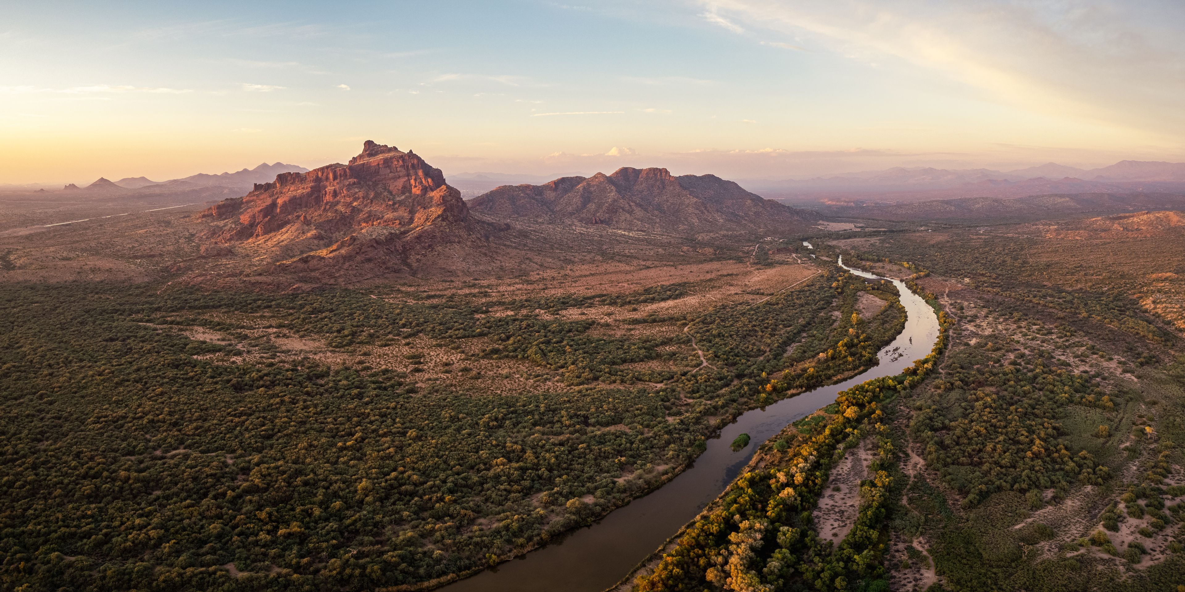Un río serpentea por un paisaje montañoso con vegetación densa y un pico rocoso destacado.